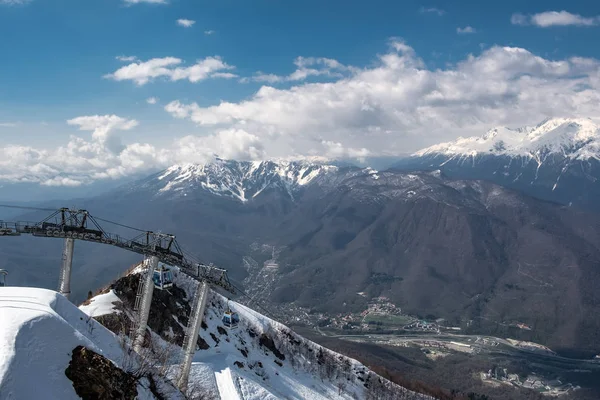 Teleférico en la cima de la montaña Aibga, en el pueblo de Krasnaya Polyana, Sochi. Cielo azul claro con nubes. Temporada turística en las montañas . —  Fotos de Stock