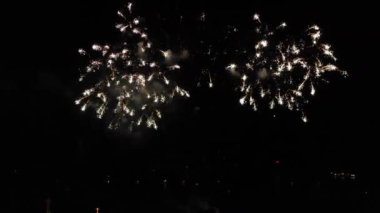 Havadan video çekimi. Gece siyah gökyüzü renkli havai fişek tatil onuruna. Denizin üzerinde havada havai fişek.