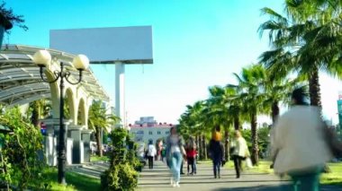 Zaman atlamalı çekim video. Yüksek düzeyde şehir merkezinde büyük Billboard 6x3. Şehir trafiği. Palmiye ağaçları yol boyunca büyür. Yürüyen sokakta. Hedef kitle.