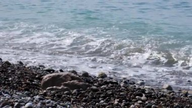Yavaş çekim modunda video çekme. Kayalık plaj. Denizin gelgiti. Deniz suyunun heyecanı. Kıyıda el sal. Plajda rahatlayın ve huzura uyabilirsiniz. Berrak mavi gökyüzü, mavi deniz suyu.
