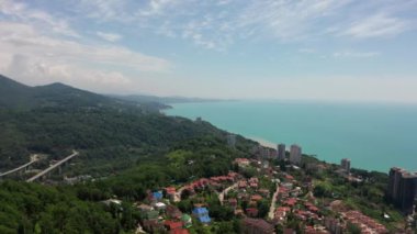 Havadan video çekimi. Bir yerleşim bölgesiüzerinde uçuyor. Soçi şehir tatil beldesi. Karadeniz kıyıları. Yeşil orman ve deniz dağları.