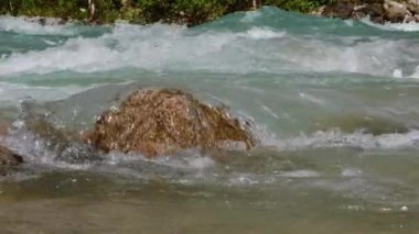 Dağ nehri hızlı bir dere akar. Yavaş çekim. Nehirde büyük bir kaya. Saf mavi su.