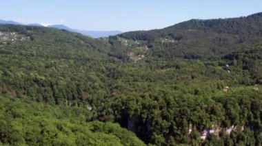 Havadan video çekimi. Soçi Milli Parkı'nın panoramik manzarası. Yukarıdan manzara. Yeşil ağaç. En yüksek dağ. Dipteki dağ nehri. Kafkasya'nın doğası.