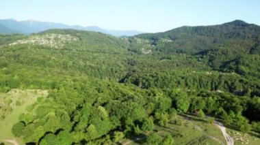 Havadan video çekimi. Dağların, tarlaların panoramik manzarası. Mavi gökyüzü. Kafkasya'nın doğası. Soçi Ulusal Parkı. Yukarıdan görünüm.