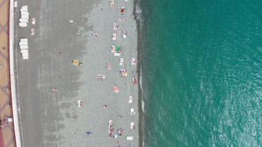 Havadan video çekimi. Aşağı bak. Tatil sezonu. Erkekler ve kadınlar plaj Imeretinsky, Sochi dinlenmek. Temiz deniz suyu. Kayalık plaj. Rekreasyon alanı. Spiral hareket.