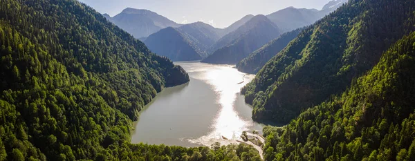 Аэрофотосъемка. Привлекательность озера Рица в Абхазии. Высокие горы, зеленые деревья, дикая природа, чистая горная вода. Панорамный снимок. Голубое небо. Высоко в горах . — стоковое фото