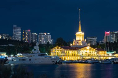 Sochi, Rusya - 02.05.2019 Soçi limanı. Binanın akşam aydınlanması. Tatil köyünün cazibesi. Yatlar ve gemiler için park yeri. Şehir görünümü.