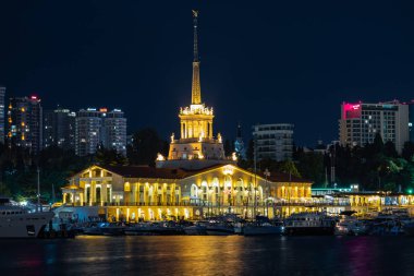 Soçi limanı. Binanın akşam aydınlanması. Tatil köyünün cazibesi. Yatlar ve gemiler için park yeri. Şehir görünümü.