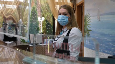 Sochi, Rusya - 06.01.2020 Koruyucu tıbbi maske takan bir kız. Resepsiyon. Otelde. Tamamen maskeli mod. Birbirinizden uzak durun. Sağlığınıza önem veriyoruz.. 