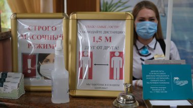 Sochi, Rusya - 06.01.2020 Koruyucu tıbbi maske takan bir kız. Resepsiyon. Otelde. Tamamen maskeli mod. Birbirinizden uzak durun. Sağlığınıza önem veriyoruz.. 