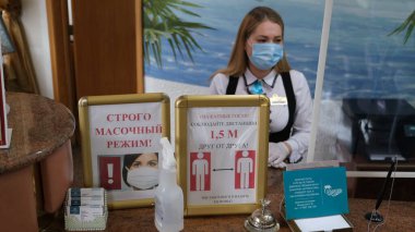 Sochi, Rusya - 06.01.2020 Koruyucu tıbbi maske takan bir kız. Resepsiyon. Otelde. Tamamen maskeli mod. Birbirinizden uzak durun. Sağlığınıza önem veriyoruz.. 