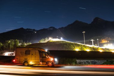 Oto yıkama. Dağlarda tekerlekli bir ev. Gece gökyüzü. Gece yol aydınlatması. Gökyüzünde yıldızlar. Huzur içinde yat. Kamp yapmak. Karavan. Karavan. - Evet. Yüksek kalite fotoğraf