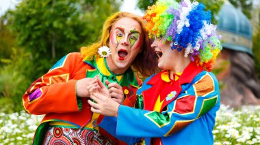 Soçi, Rusya - Haziran 07.2020: Çiçek tarlasında iki palyaço adam ve kadın. Fotoğraf çekimi. Sochi Parkı. Karnaval. Sirk. Açık havada. Makyaj. Tatil günü. Maskeli balo. Eğlenceli.. 