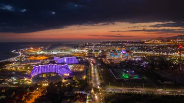 Sochi, Rusya - 20 Haziran 2020: Sochi Parkı. Sirius. Bogatyr. Fisht Stadyumu. Hava fotoğrafı. Gün batımı. Binanın akşam aydınlatması. Işıklandırma
