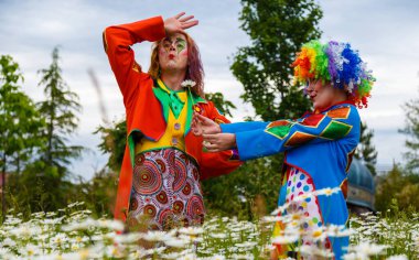 Soçi, Rusya - Haziran 07.2020: Çiçek tarlasında iki palyaço adam ve kadın. Fotoğraf çekimi. Sochi Parkı. Karnaval. Sirk. Açık havada. Makyaj. Tatil günü. Maskeli balo. Eğlenceli.. 