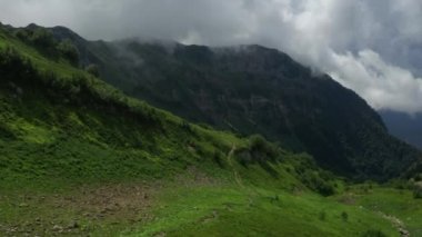 Alp dağlarının hava görüntüsü. Dağlar, tepeler, uçurumlar, kayalar, çıkıntılar, manzara, yeşil çimenler, gökyüzü, bulutlar, doğa, işlenmemiş doğa, drone videosu.