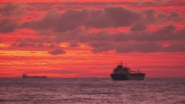 Denizdeki nakliye gemisi. Güzel turuncu gün batımı. İyi akşamlar. Deniz yoluyla nakliye. Konteyner gemisi. 