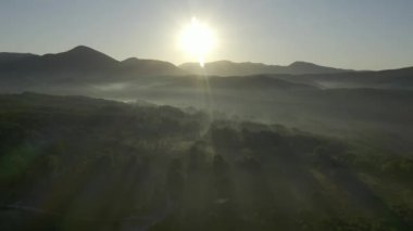 Kırsal kesimde sabahın erken saatlerinde aydınlık bir şafak. Sıcak sabah güneşi altında doğal vahşi doğanın manzarası. Sis içinde gün doğumu şafağın altın ışığı. Doğa. Hava görünümü. 