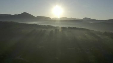 Kırsal kesimde sabahın erken saatlerinde aydınlık bir şafak. Sıcak sabah güneşi altında doğal vahşi doğanın manzarası. Sis içinde gün doğumu şafağın altın ışığı. Doğa. Hava görünümü. 