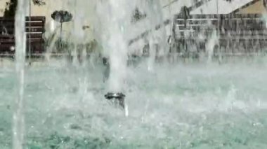 Damlaların ve fıskiyedeki su damlalarının yakın görüntüsü. Çeşmedeki mavi su parıldıyor ve parlıyor..