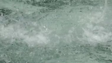 Damlaların ve fıskiyedeki su damlalarının yakın görüntüsü. Çeşmedeki mavi su parıldıyor ve parlıyor..