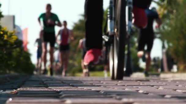 在靠近海洋的沿海城市 骑自行车的人或游客在自行车道上骑自行车 跑步者腿模糊 复制空间 马拉松 一群人在跑步 — 图库视频影像