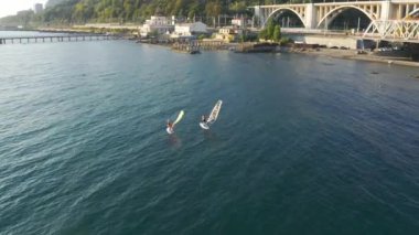 Erkek ve kadın mayolu bir adam yemek masasında duruyor ve yüzen sporcu arkadaşlar için yüzme küreğiyle denizde yüzüyor. Sochi, Rusya. hava durumu