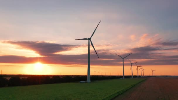 Letecký pohled na větrné turbíny stojící při západu slunce. farmy s větrnými turbínami. Vytváření čisté obnovitelné energie. jasně oranžový větrný park západu slunce zpomaluje. Alternativní energie — Stock video