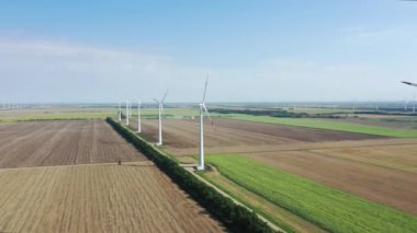Elektrik üreten rüzgar türbinleri. Rüzgâr değirmeni güç teknolojisi. Enerji Üretiminde hava aracı görüntüsü. Rüzgâr türbinleri çiçek açan bir arazide duruyor. Yeşil alan. Kapat..