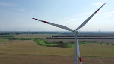 Elektrik üreten rüzgar türbinleri. Rüzgâr değirmeni güç teknolojisi. Enerji Üretiminde hava aracı görüntüsü. Rüzgâr türbinleri çiçek açan bir arazide duruyor. Yeşil alan. Kapatın. Havadan üst görünüm. 