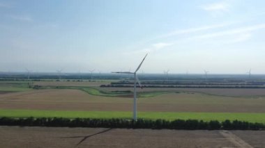 Elektrik üreten rüzgar türbinleri. Rüzgâr değirmeni güç teknolojisi. Enerji Üretiminde hava aracı görüntüsü. Rüzgâr türbinleri çiçek açan bir arazide duruyor. yeşil alan.