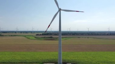 Elektrik üreten rüzgar türbinleri. Rüzgâr değirmeni güç teknolojisi. Enerji Üretiminde hava aracı görüntüsü. Rüzgâr türbinleri çiçek açan bir arazide duruyor. yeşil alan.