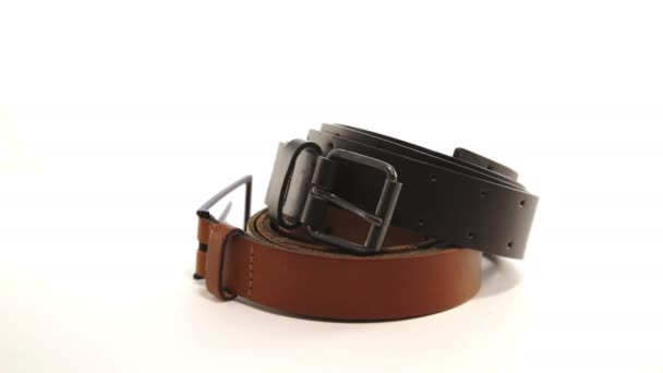 Two leather belts with buckles rotate on white background — Stock Video