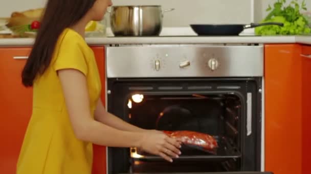 Young woman prepares meat in oven — Stock Video