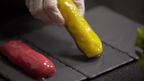 Confectioner puts yellow glaze eclair on stone plate — Stock Video