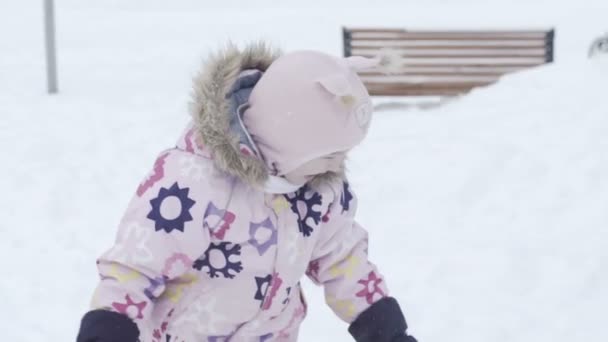 Uśmiechający się trochę rgirl, grając z śniegu — Wideo stockowe