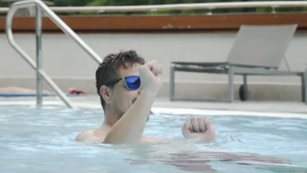 Vrolijke man in zonnebril is dansen in het zwembad op zomer feest — Stockvideo