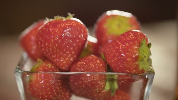 Fresas rojas en un tazón de vidrio sobre mesa giratoria — Vídeo de stock