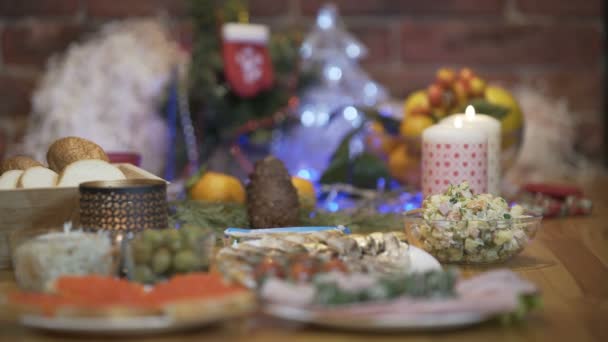 Mani che si mettono un tavolo festivo Olivie su sfondo dell'albero di Natale — Video Stock