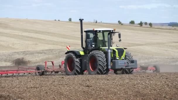 Фермерский трактор движется по сельскохозяйственному полю для вспашки земли. Сельскохозяйственное тракторное поле — стоковое видео