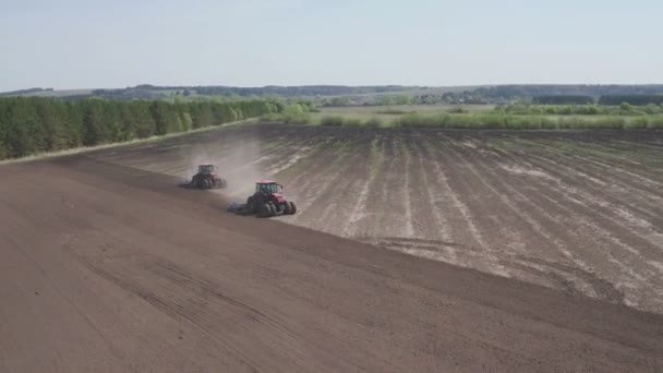 Вид с воздуха на два трактора, идущих в противоположном направлении и обрабатывающих землю. Сельскохозяйственное тракторное поле — стоковое видео