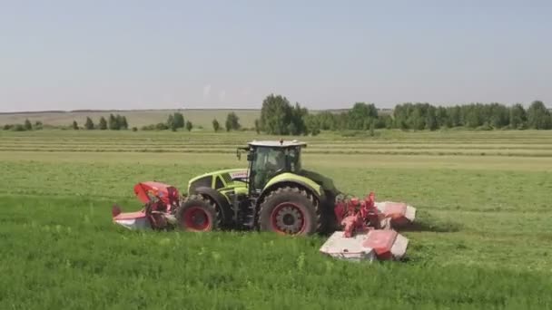 Вид з повітря, що літає над вершиною комбайнів він спотворює траву в полі в літній день — стокове відео