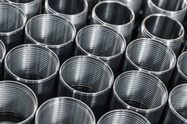 Pattern of metal cylinders stand on table at factory. Steel products to automotive industry. Billet obtained on lathe from steel and cast iron. Circular precision steel parts arranged in rows