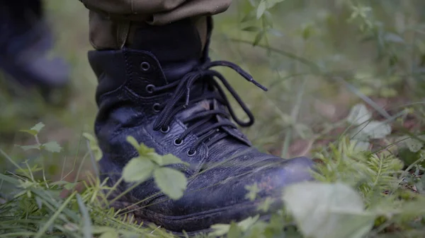 Man walking on mossy forest path. Outdoor activity concept. Summer hiking in wilderness area. Closeup of legs in hiking boots. Man hunter outdoor in forest hunting alone.