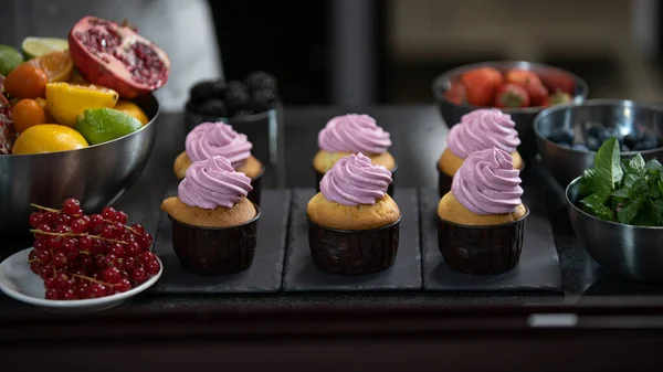 Decorating cup cake with cream. Confectioner making muffins. Modern desserts and cakes. Cupcakes with cream filling. Professional pastry. Stock Image