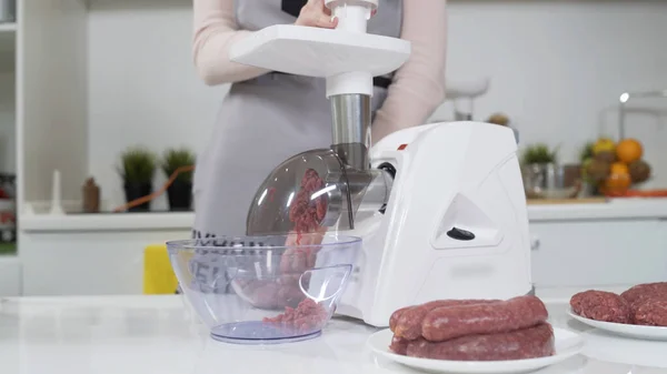Making minced meat in electric meat grinder from fresh beef at home. Pile of chopped meat. Electric mincer machine with fresh chopped meat. Preparation of minced beef with an electric meat grinder.