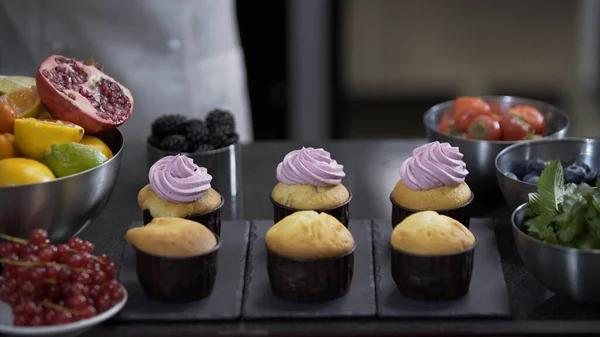 Decorating cup cake with cream. Using cooking bag, confectioner making muffins. Modern desserts and cakes. Cupcakes with cream filling. Professional pastry. Stock Image