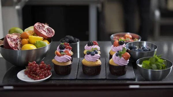 Professional pastry. Decorating cup cakes with mint, strawberry and blueberry. Beautiful cake for a holiday Stock Photo