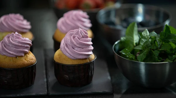 Decorating cup cake with cream. Confectioner making muffins. Modern desserts and cakes. Cupcakes with cream filling. Professional pastry. Stock Photo