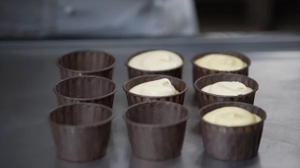 Put dough into paper cups. Hand pouring cake dough into muffin tray Stock Image